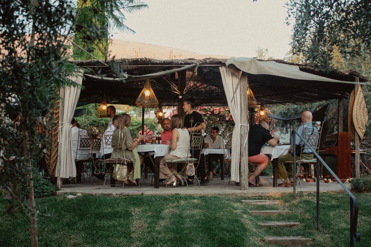 Guests dining under the pergola at dusk